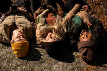 Male and female friends wearing knit hat taking rest on rock during sunny day