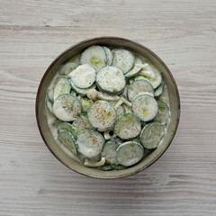 Homemade Cucumber Salad with Sour Cream and Onions in a Bowl, top view. Flat lay, overhead, from above.