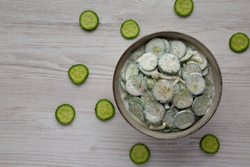 Homemade Cucumber Salad with Sour Cream and Onions in a Bowl, top view. Flat lay, overhead, from above. Copy space.