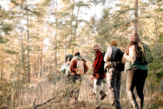 Friends walking in row while hiking together at forest