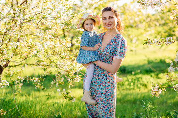 a mother and little daughter in a hat on a walk in the spring garden. 