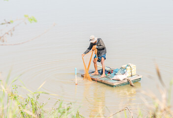 Asian man wash fishnet after castnet in canal..