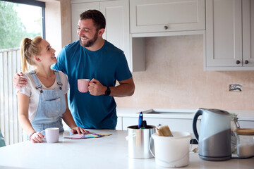 Couple Renovating Kitchen At Home Looking At Paint Swatches On Coffee Break