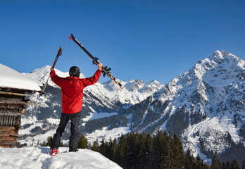 Skifahrer, Tourengeher, Skibergsteiger  jubelt in Siegerpose vor Bergpanorama im Winter