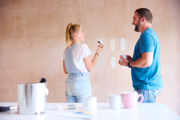 Couple Renovating Kitchen At Home Painting Tester Paint Colour Strips On Wall