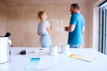 Obraz premium Focus On Foreground As Couple Renovating Kitchen At Home Paint Tester Paint Colour Strips On Wall