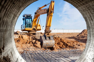 A powerful caterpillar excavator digs the ground against the blue sky. Earthworks with heavy...
