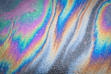 Fototapeta na wymiar Oil stain on the asphalt, rainbow-shaped colored gasoline stains on an asphalt road