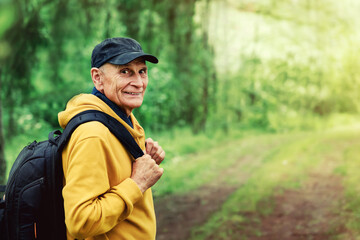 Lonely mature male tourist with backpack walking at forest