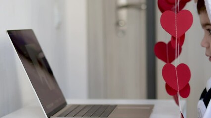 kid or woman putting on wall red paper hearts garland or using laptop web cam to show someone social media communication.woman hand get ready garland to hang inside home.celebrate valentine love day 4