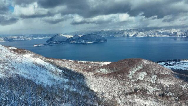 winter in Hokkaido, Japan, aerial view of snowy mountains round volcanic lake Toya, tourism in the north of Japan, cold frosty beautiful winter landscape