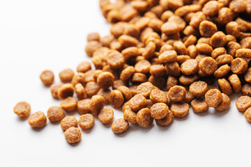 Dry feed pellets for dogs on a white background.