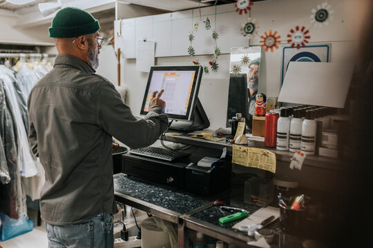 Rear view of male tailor using computer in workshop