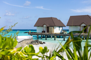 House on stilts in the indian ocean with blue sky and crystal clear water on sandy beach coast