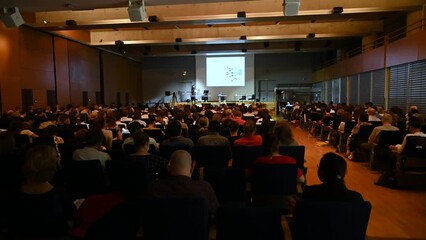 4K video of Science, Business and entrepreneurship symposium. Speaker giving a talk at scientific meeting. Audience in conference hall. Rear view of unrecognized participant in audience.