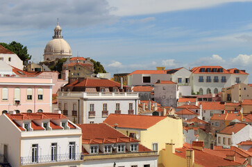 Obraz premium Exterior view of beautiful historical buildings, rooftops, and church towers in downtown Lisbon, Portugal Europe. Colorful Mediterranean street with old townhouses in Alfama neighborhood.