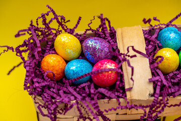 Easter composition from a basket and colored eggs prepared for the holiday on a yellow background