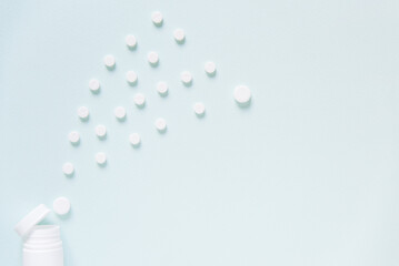 Scattered white pills on blue table. Mock up for special offers as advertising, web background or other ideas. Medical, pharmacy and healthcare concept. Copy space. Empty place for text or logo