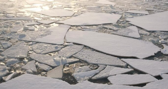 Winter river covered with crushed ice and water from which steam emanates. Glare of the sun and sparkling ice.
