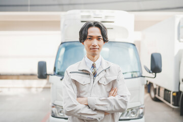 Fototapeta premium トラックの前で腕組みをする若い男性ドライバー