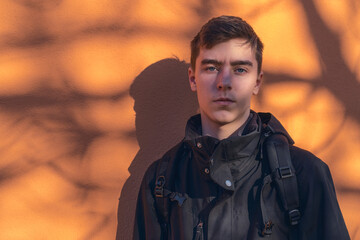 portrait of a serious young man in front of an orange wall with