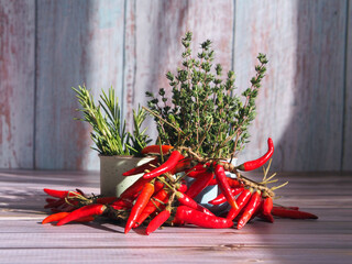 Fresh thyme, rosemary and red chili  against a wooden rustic background.