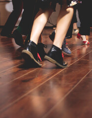 Dancing shoes of young couple dance retro jazz swing dances on a ballroom club wooden floor, close up view of shoes, female and male, dance lessons class rehearsal