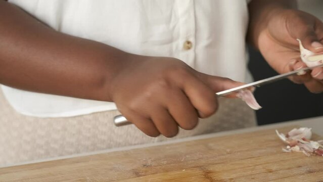 Close up of cuban woman hands peeling a raw garlic using a knife.