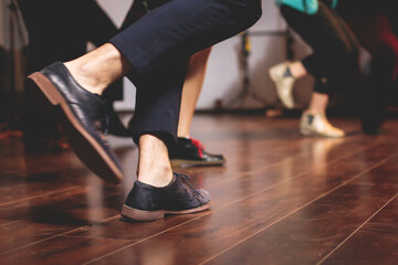 Dancing shoes of young couple dance retro jazz swing dances on a ballroom club wooden floor, close up view of shoes, female and male, dance lessons class rehearsal