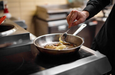 man chef cooking fried shrimp in frying pan on kitchen