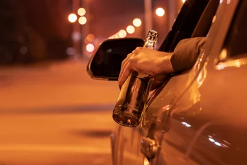 Fototapete Schiffswrack Drunk man driving a car with a bottle of beer at the night. Don't drink and drive concept