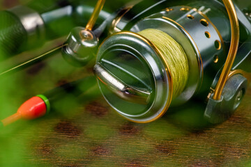 Fishing theme. Reel, rod, fishing buoy, feeder, and fishing net on wooden background.