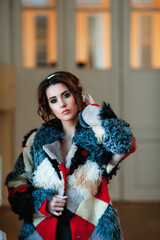  sexy girl dressed in a fur coat and posing indoors on the background of the door; warm long fur coat