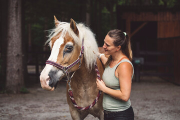 Woman petting a beautiful colorful horse, holding him for a leash, going horse back riding