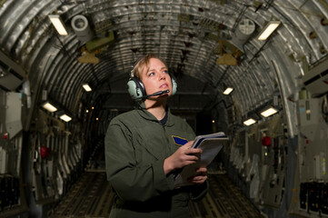 A U.S. Air Force loadmaster runs down her checklist in the cargo area during preflight.