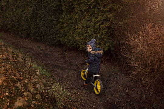 Toddler boy in warm jacket on a push bike with yellow wheels