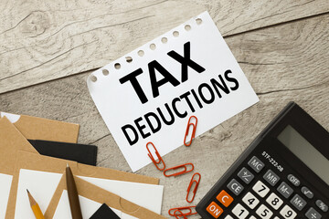 Tax Deductions text on white paper. red paper clips and calculator