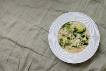 Italian risotto with broccoli and parmesan cheese on light background. Top view with copy space.