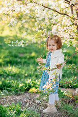 a little girl by a flowering tree in a spring garden