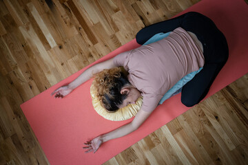 One adult caucasian woman practice restorative yoga at home