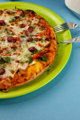 Pizza with meat, bacon, sausages, sausage, parmesan and dill, cheese, sauce. Food in a plate on a blue background. Menu. Homemade pastries. Meal with meat. Food on the table.