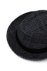 Close-up subject shot of a checkered trilby hat adorned at the crown with a wide black ribbon. A stylish plaid grey mid-season hat is isolated on the white backdrop.
