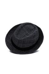 Subject shot of a checkered trilby hat adorned at the crown with a wide black ribbon. A stylish plaid grey mid-season hat is isolated on the white backdrop.
