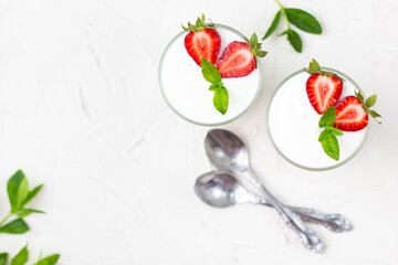 Healthy strawberry yogurt with in glasses with fresh berries over white table.