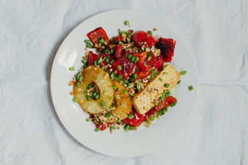 Healthy vegetarian lunch from tofu cheese, vegetables and nuts on light background. Top view. Free space for your text.