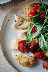 Fried chicken fillet and fresh vegetable salad of tomatoes and arugula leaves.