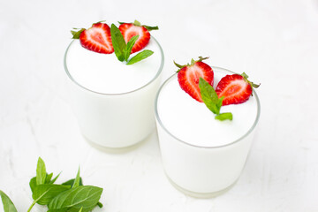 Healthy strawberry yogurt with in glasses with fresh berries over white table.