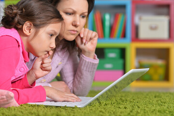 Mother with her little daughter using laptop