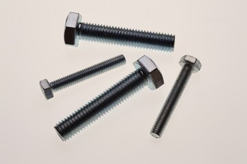 New, chrome-plated bolts and nuts of different sizes lie on a white background. Close-up