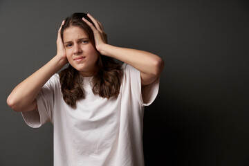 Fototapeta premium Worried woman with sullen eyebrows holding her head in hands